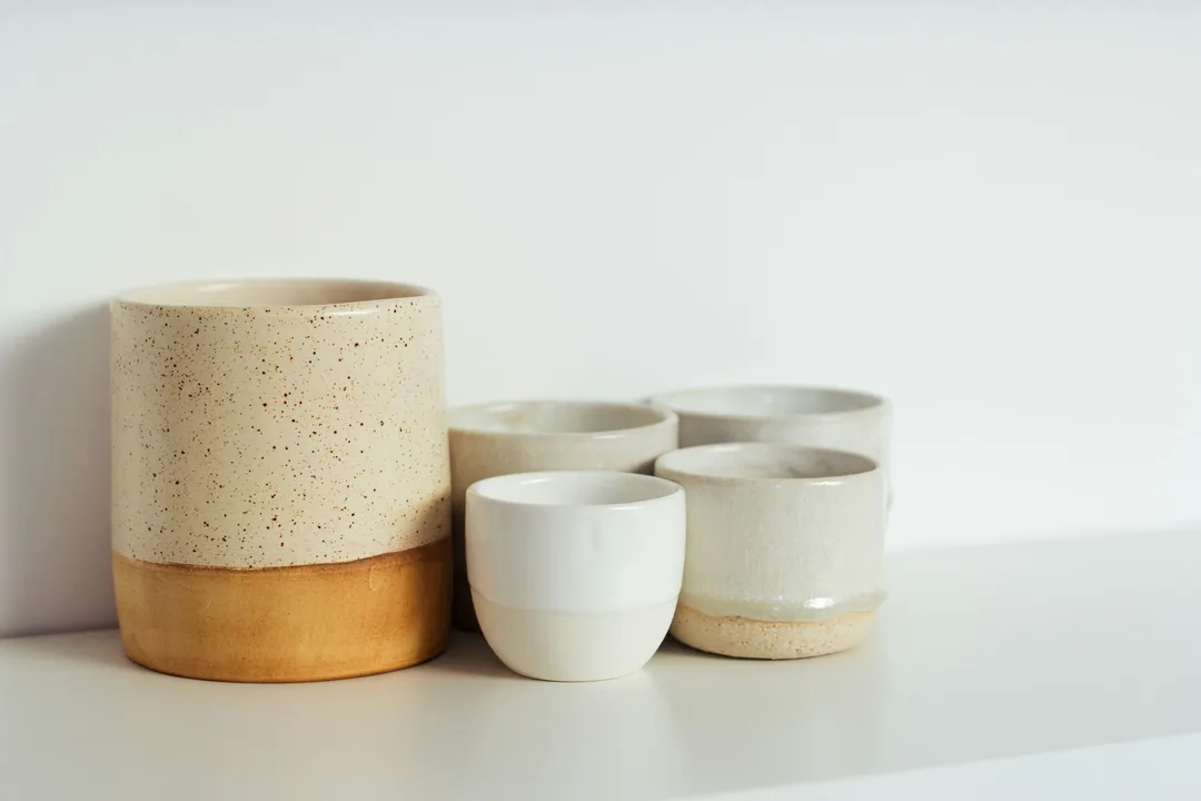 Speckled handmade cups on a white shelf