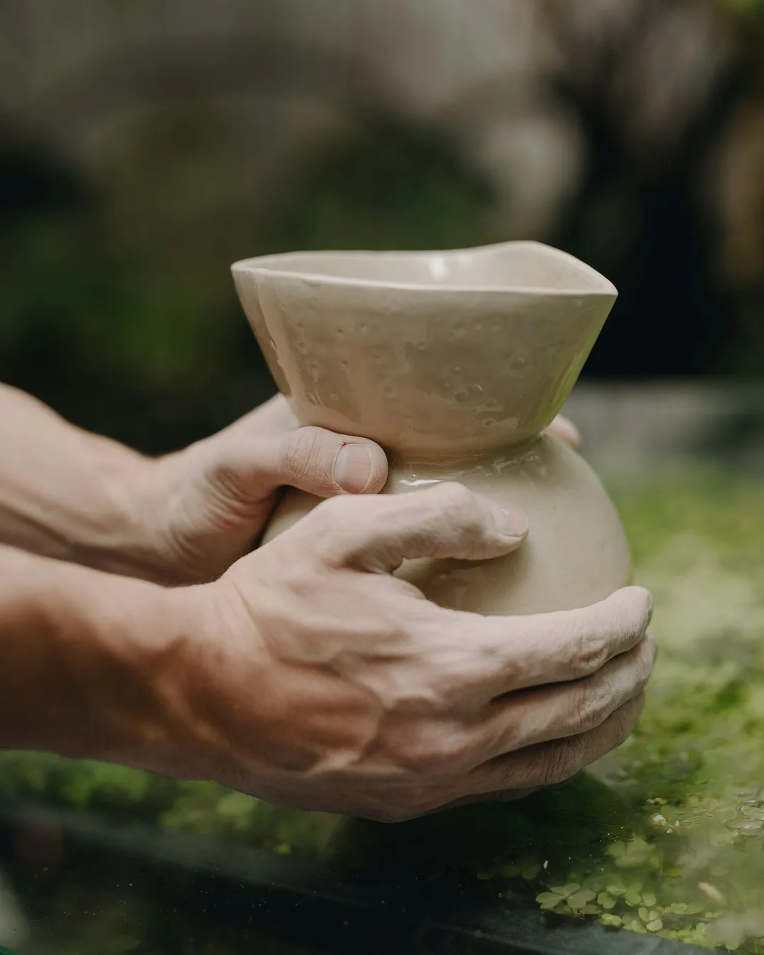 Hands holding a pale glazed vase