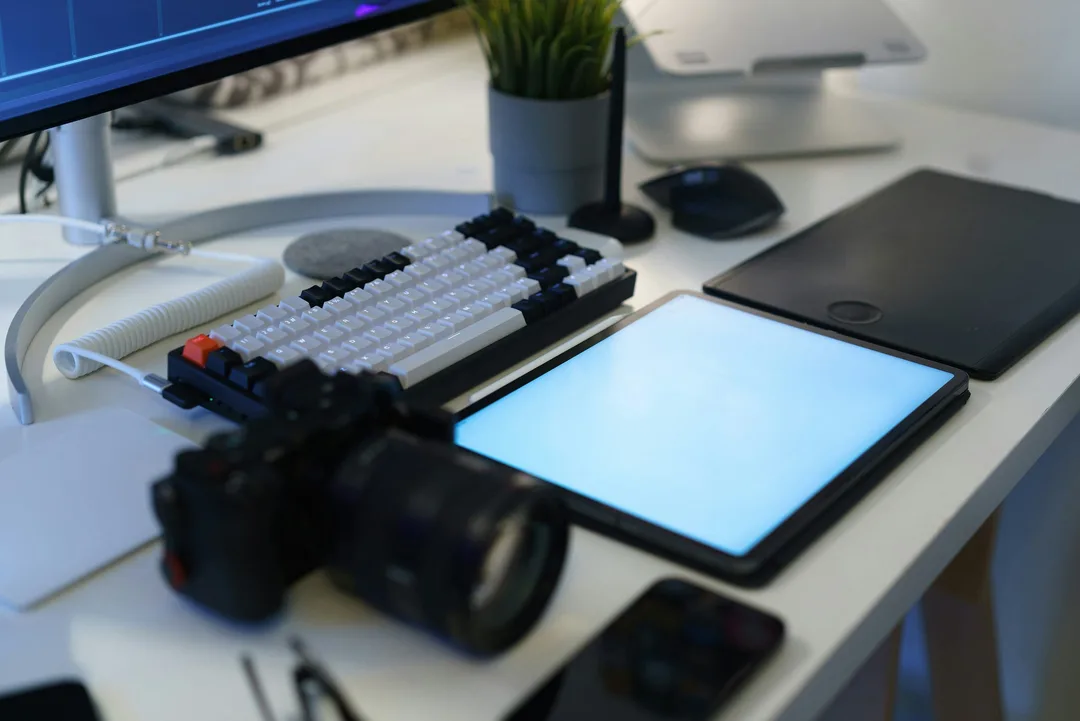 A desk with a camera, a keyboard and a tablet