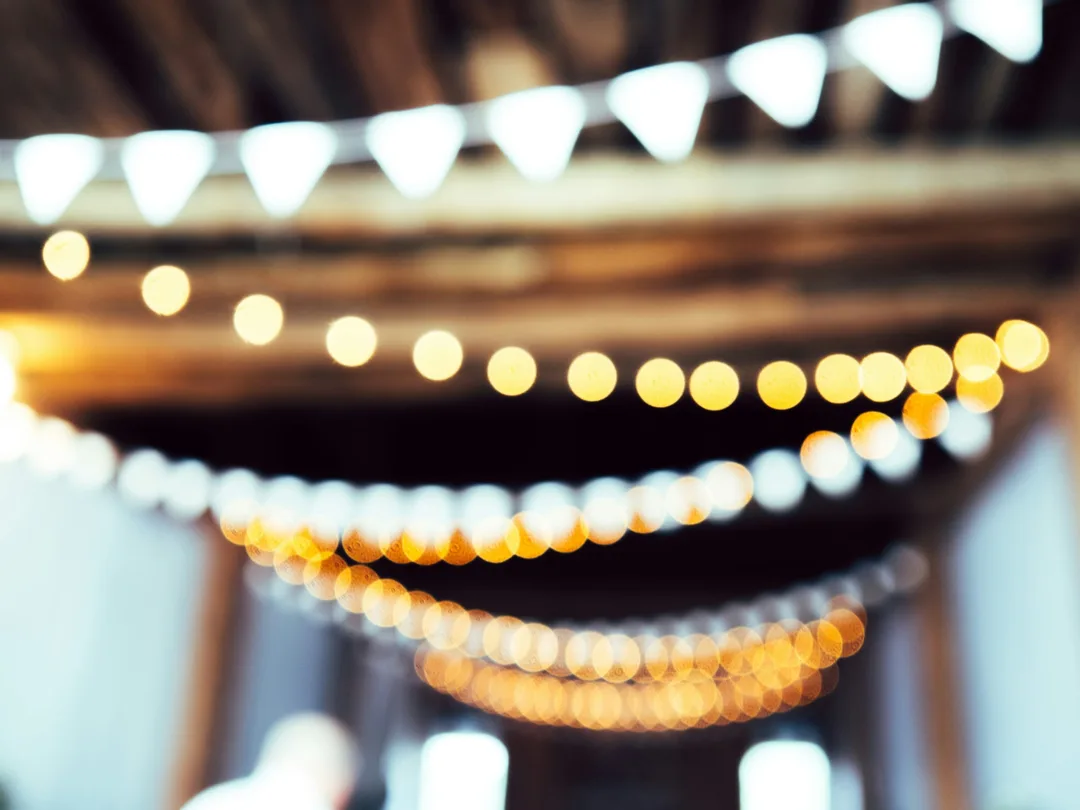 Strings of warm lights glowing out of focus above a hall