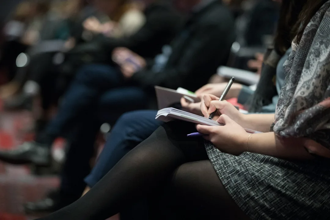 Hands holding a pen over a notepad during a talk
