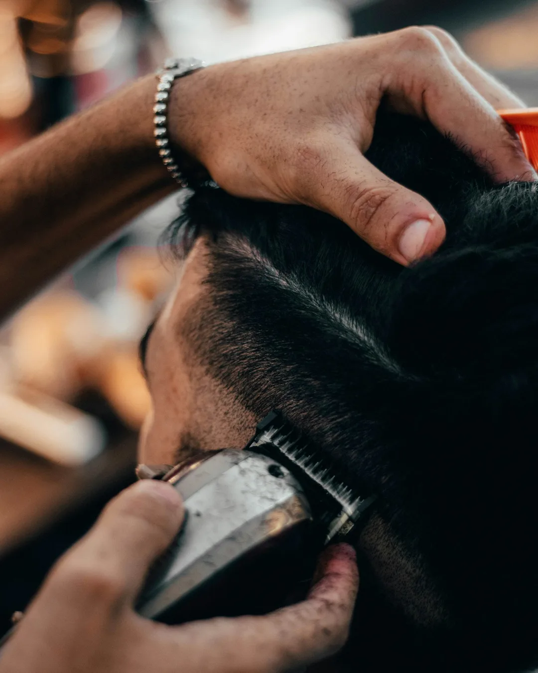 A barber trimming a fade with clippers