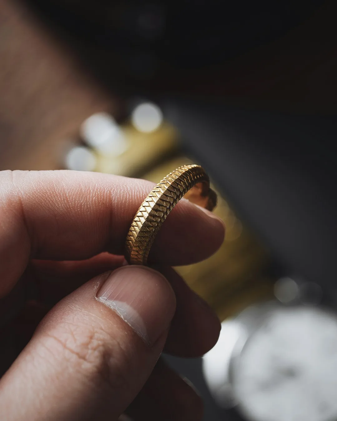 Fingers holding a woven gold ring
