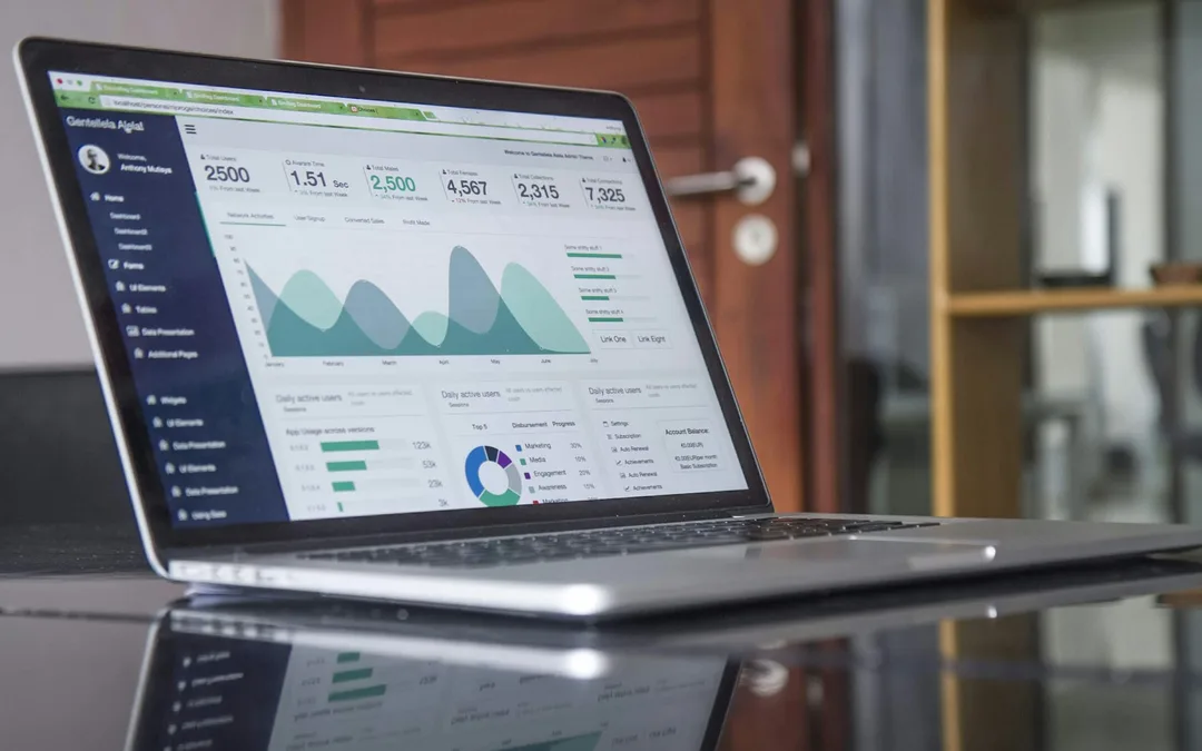 A laptop on a glass table showing a business dashboard with charts