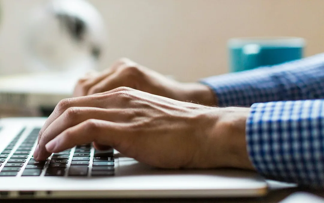 Hands typing on a laptop keyboard