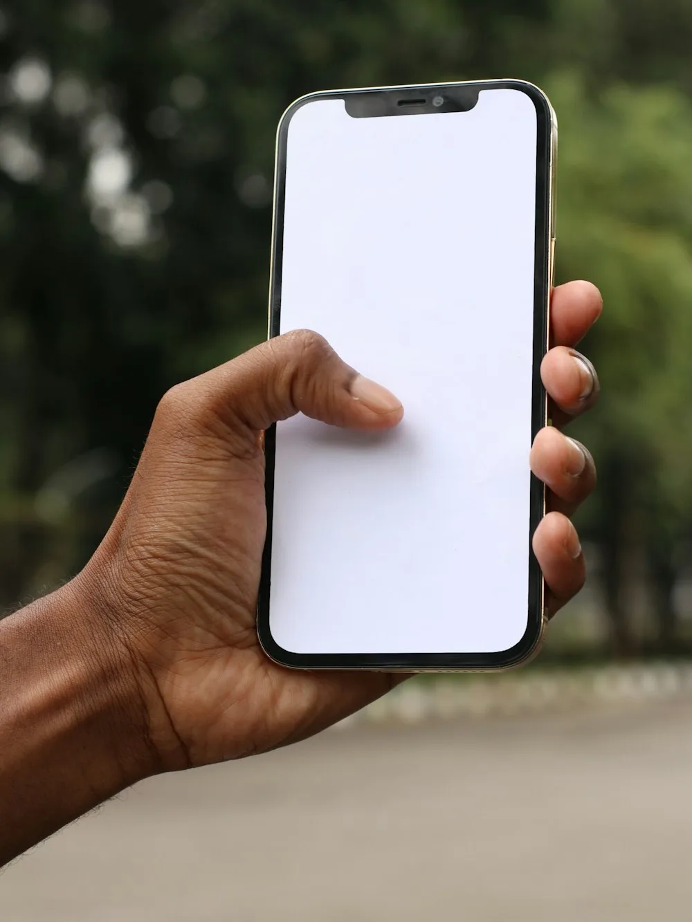A hand holding a phone with a blank screen, outdoors