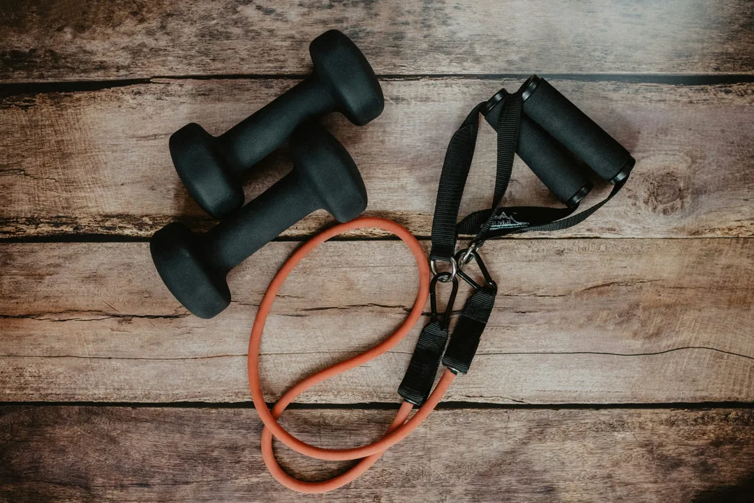 Two dumbbells and a resistance band on a wooden floor